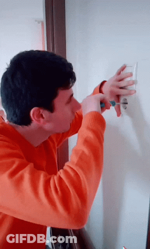 Man In Orange Sweater Holding Green Screwdriver GIF
