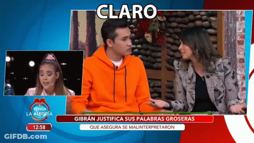 Man In Orange Sweatshirt Talking To Woman On TV Claro GIF