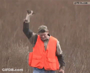 Man In Orange Vest Holding Rifle In Field GIF