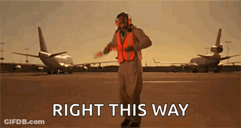 Man In Orange Vest On Runway Says Right This Way GIF