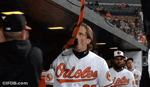 Man In Orioles Jersey Holding Bat In Mouth GIF