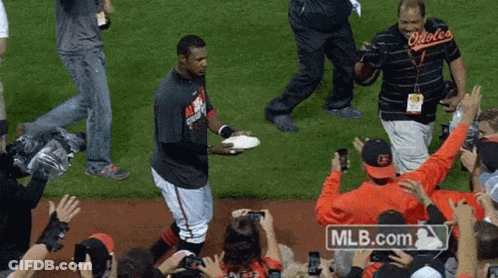 Man In Orioles Shirt Holding Plate In Crowd GIF