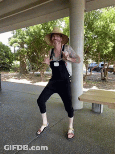 Man In Overalls And Straw Hat Standing On One Leg GIF
