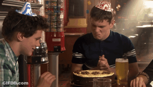 Man In Party Hat Sitting At Table With Pizza GIF