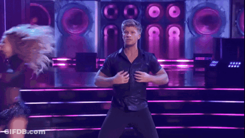 Man In Pink And Blue Shirt Beside Woman In Black Dress GIF