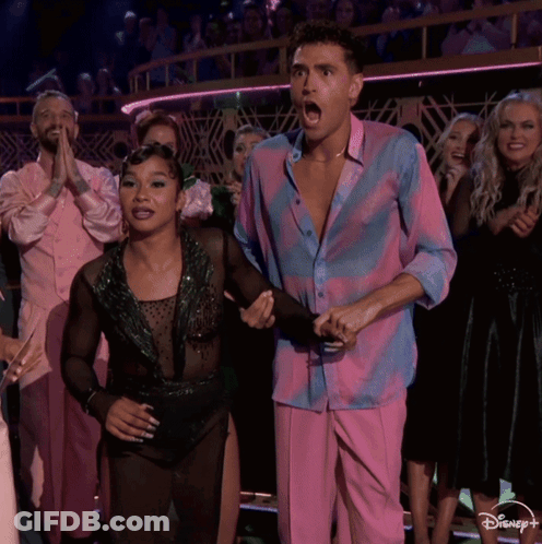 Man In Pink And Blue Shirt Beside Woman In Black Dress GIF