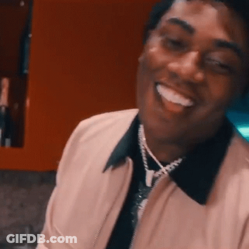 Man In Pink Jacket And Necklace Smiling GIF