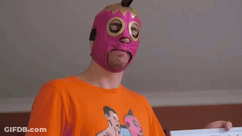 Man In Pink Mask And Orange Shirt Holding Paper GIF