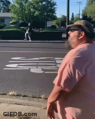 Man In Pink Shirt And Hat On Sidewalk GIF