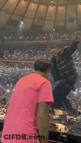 Man In Pink Shirt Before Crowd, Singer With Mic GIF