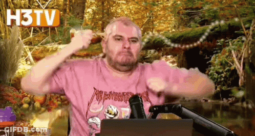 Man In Pink Shirt Holding Stick At Microphone GIF