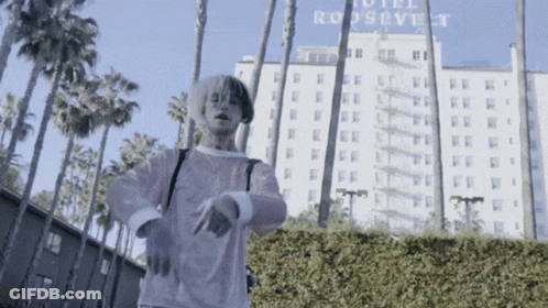 Man In Pink Shirt In Front Of Hotel Roosevelt GIF