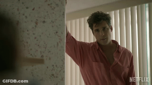 Man In Pink Shirt Standing By Netflix Window GIF