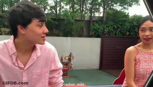 Man In Pink Shirt Talking To Woman In Red GIF