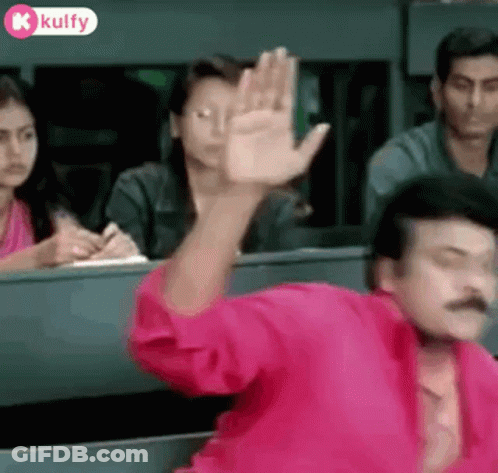 Man In Pink Shirt Waving In Classroom GIF