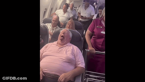 Man In Pink Shirt Yawning On Airplane GIF