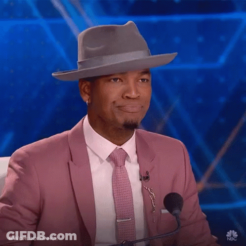 Man In Pink Suit And Tie Sitting At Microphone GIF