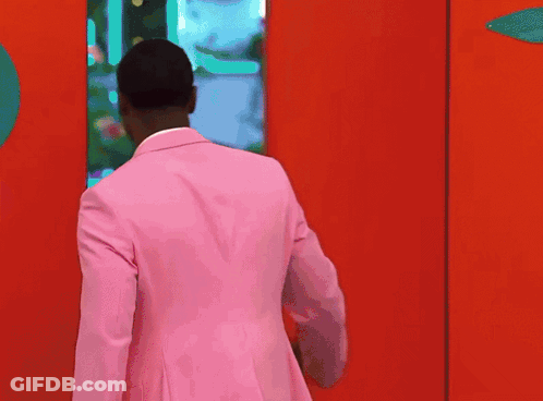 Man In Pink Suit In Front Of Red Door GIF
