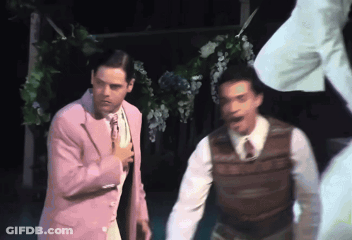 Man In Pink Suit Next To Man In Brown Vest GIF
