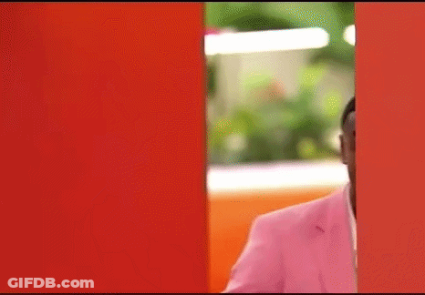 Man In Pink Suit Peeking Out Of Red Wall GIF