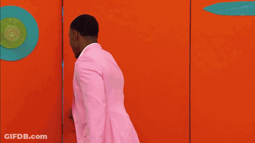 Man In Pink Suit Walking Through Doorway GIF