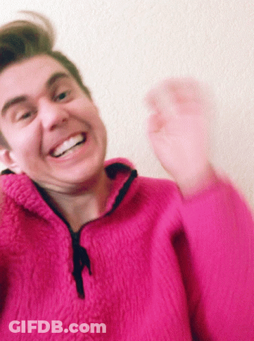 Man In Pink Sweater Smiling And Waving GIF