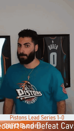 Man In Pistons T-Shirt In Front Of Framed Jersey GIF