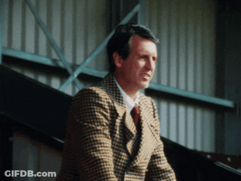 Man In Plaid Jacket And Tie Standing In Front Of Building GIF