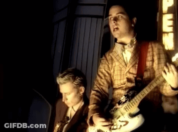 Man In Plaid Jacket Playing Guitar Beside Man In Suit GIF
