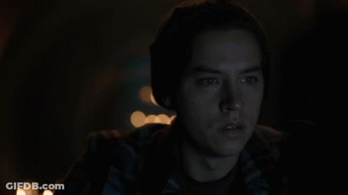 Man In Plaid Shirt And Beanie Looking At Camera In Dark GIF