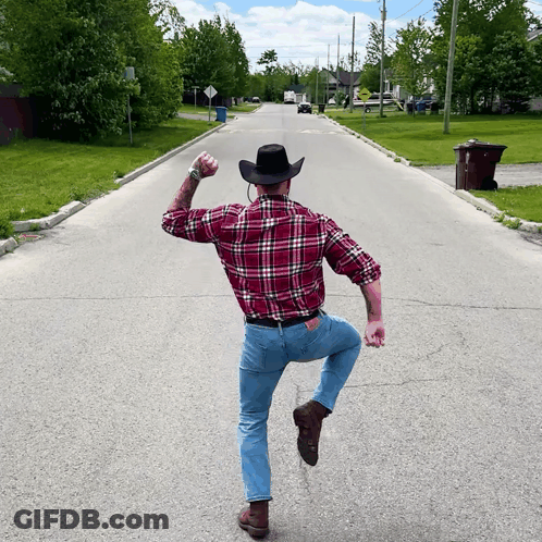 Man In Plaid Shirt And Cowboy Hat Standing On One Leg GIF