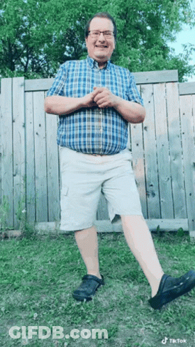 Man In Plaid Shirt And Shorts By Fence GIF