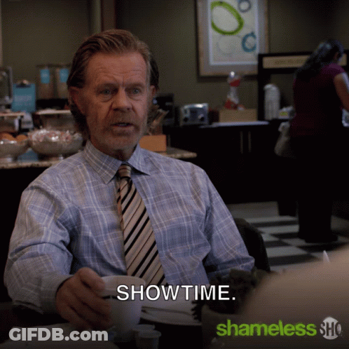 Man In Plaid Shirt And Tie At Table With Showtime GIF