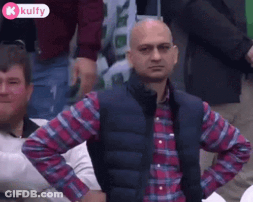 Man In Plaid Shirt And Vest With Hands On Hips In Crowd GIF