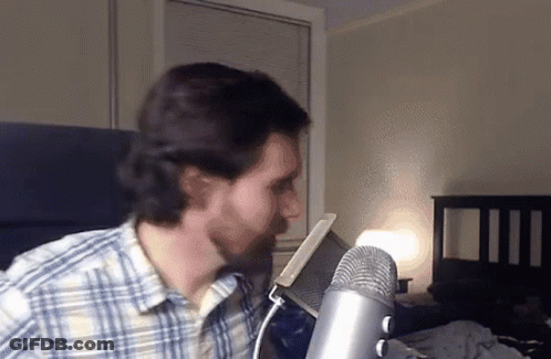 Man In Plaid Shirt At Microphone GIF