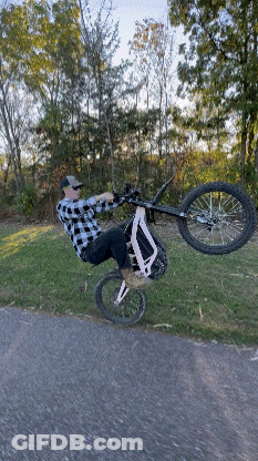 Man In Plaid Shirt Doing Bike Trick GIF