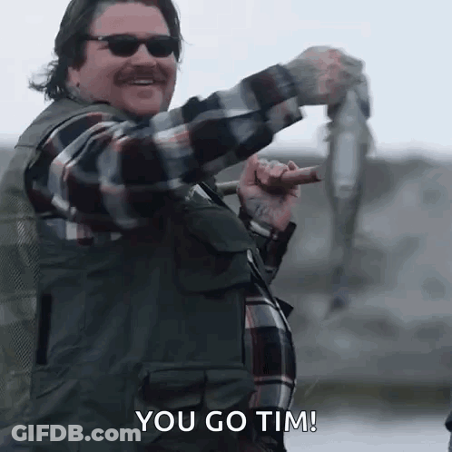 Man In Plaid Shirt Holding Fish And Fishing Rod GIF