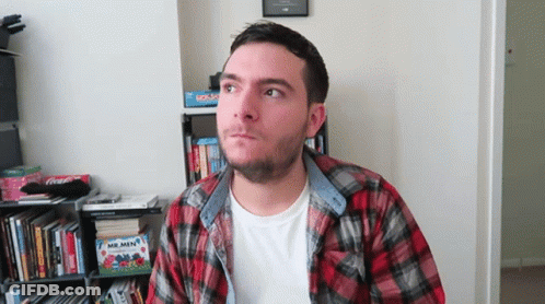 Man In Plaid Shirt In Front Of Bookshelf GIF