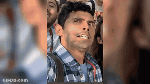 Man In Plaid Shirt Making Funny Face In Crowd GIF