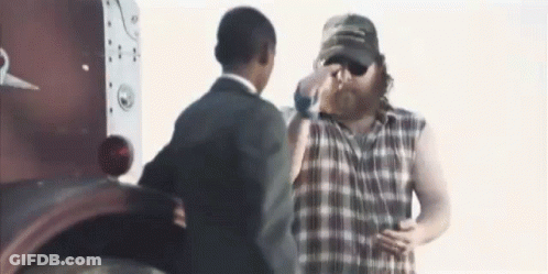 Man In Plaid Shirt Next To Man In Suit And Hat GIF