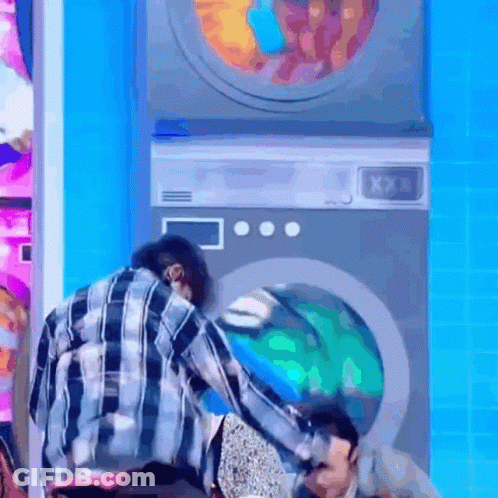 Man In Plaid Shirt Next To Washing Machines GIF