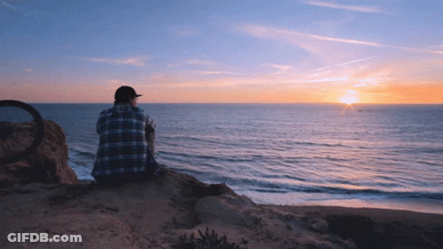Man In Plaid Shirt On Cliff Overlooking Ocean GIF
