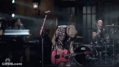 Man In Plaid Shirt Playing Red Guitar On Stage GIF