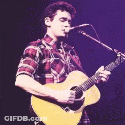 Man In Plaid Shirt Singing Into Microphone Holding Guitar GIF