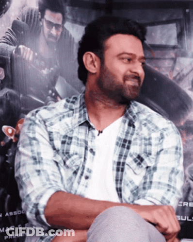 Man In Plaid Shirt Sits In Front Of Mar & E Press Poster GIF