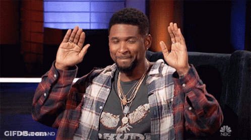 Man In Plaid Shirt Sitting In Chair With Hands Up And NBC Logo GIF