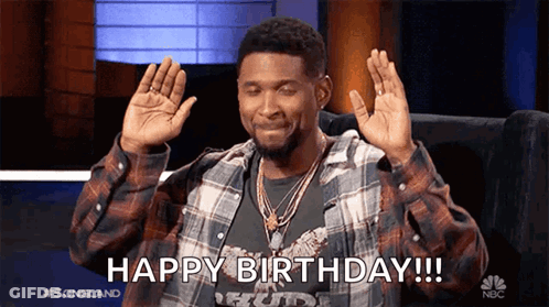 Man In Plaid Shirt Sitting With Hands Up Says Happy Birthday GIF