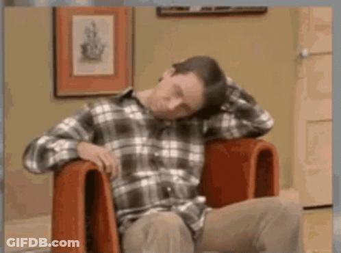 Man In Plaid Shirt Sitting With Head On Hands GIF