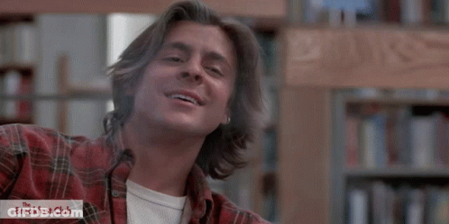 Man In Plaid Shirt Smiling In Front Of Breakfast Club Logo GIF