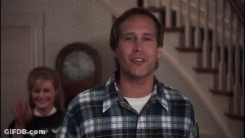 Man In Plaid Shirt Standing In Front Of Clock GIF